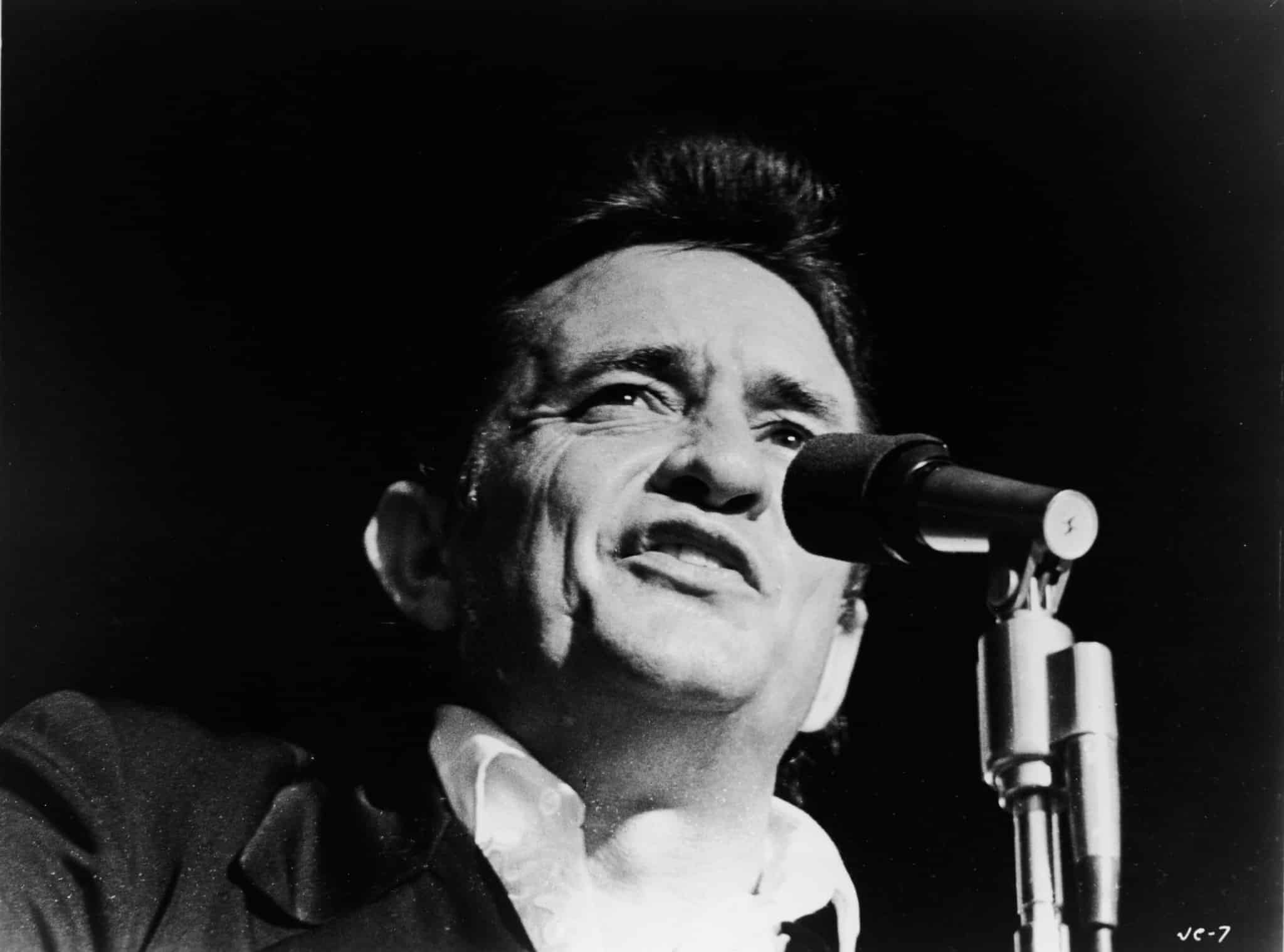 Headshot of American country singer Johnny Cash (1932 - 2003) singing on stage in a still from the film, 'Johnny Cash - The Man, His World, His Music,' directed by Robert Elfstrom, 1969. 