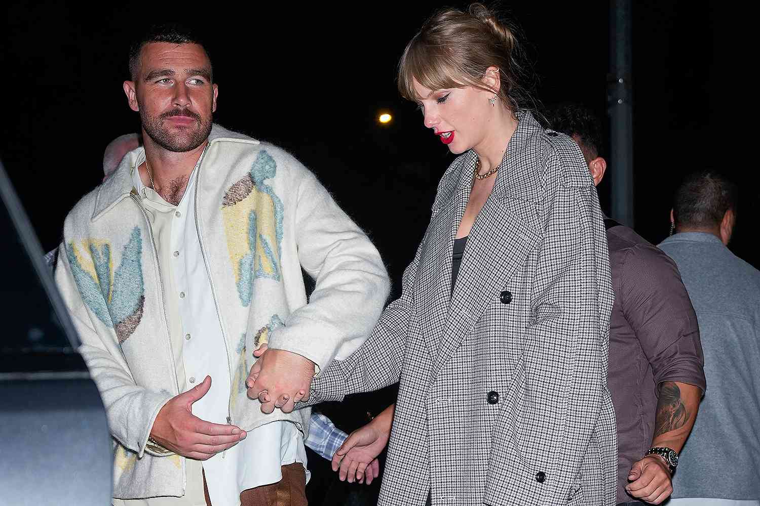 Taylor Swift and Travis Kelce holding hands.