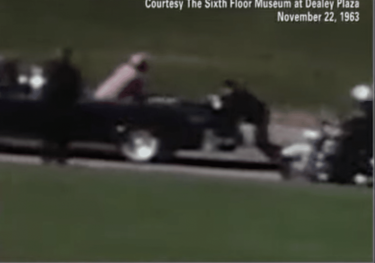 Clint Hill is seen climbing onto the back of the presidential limousine carying JFK and Jacqueline Kennedy.