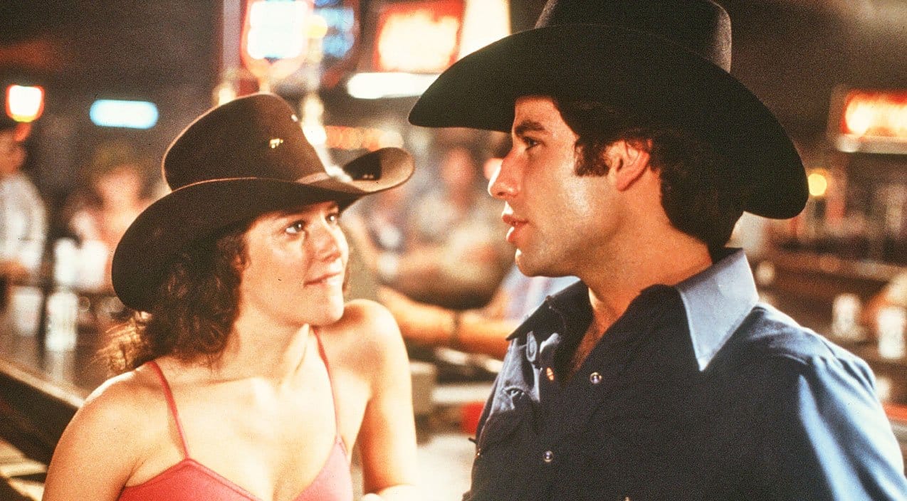 John Travolta and Debra Winger in Urban Cowboy, which you can learn some fun facts about in this list