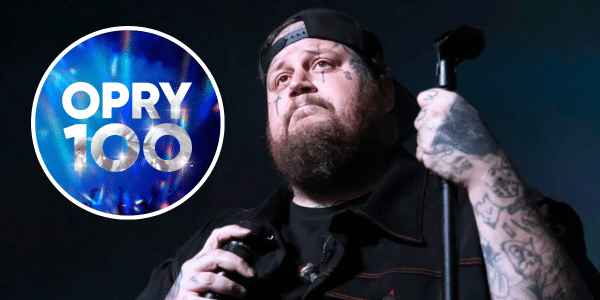 Jelly Roll makes an emotional expression onstage, alongside an inlay of the Opry 100 logo in blue.