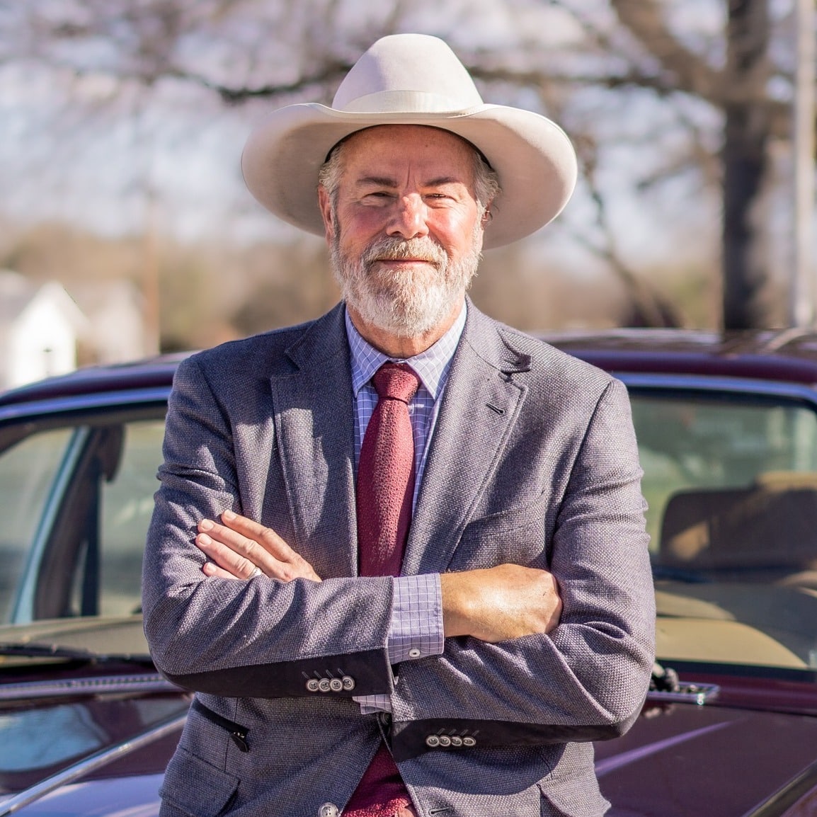 Country singer Robert Earl Keen poses, arms crossed, in front of a car