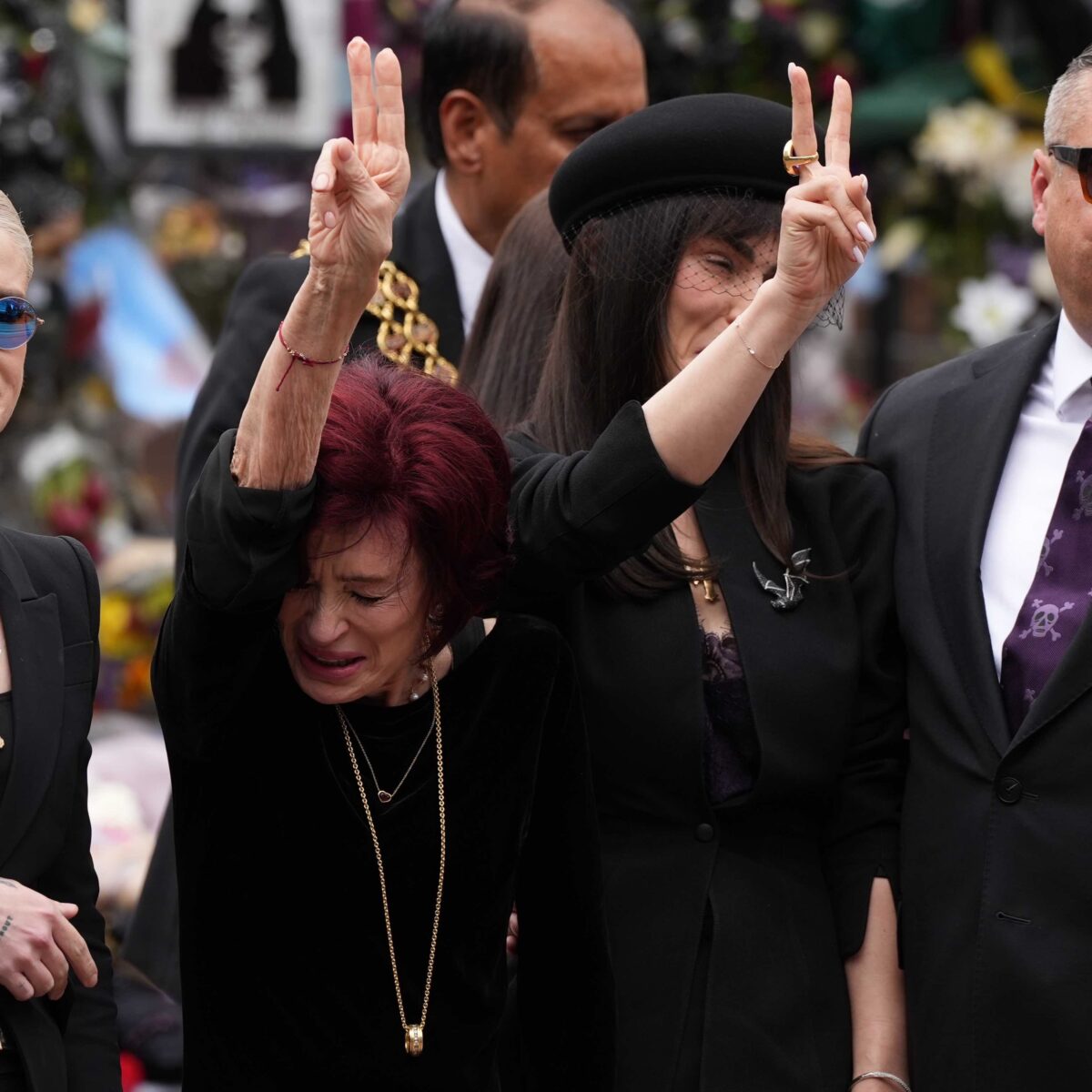 Sharon Osbourne flashes peace signs to the crowd along the route of Ozzy's funeral procession