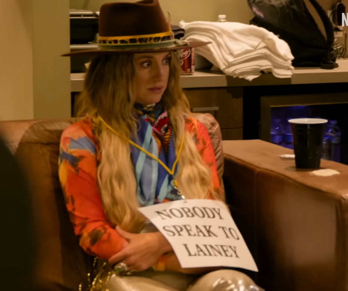 Lainey Wilson wears a sign that reads, "Nobody Speak To Lainey" 