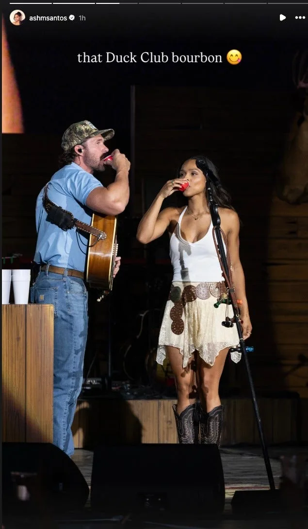 Riley Green and Ash Santos share a shot together on stage 